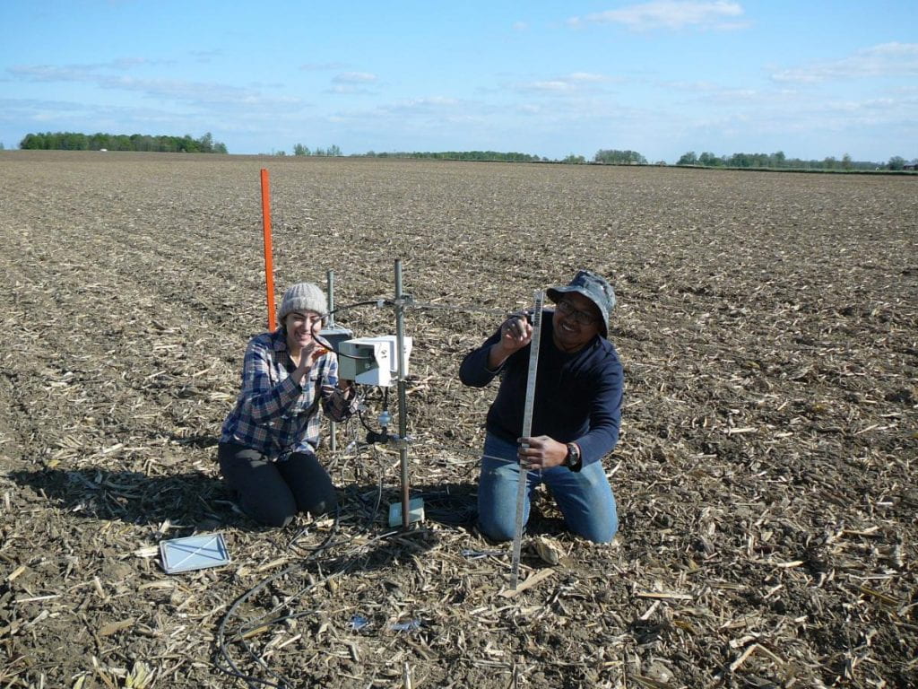 Two people in the field setting up flux measurement equipment