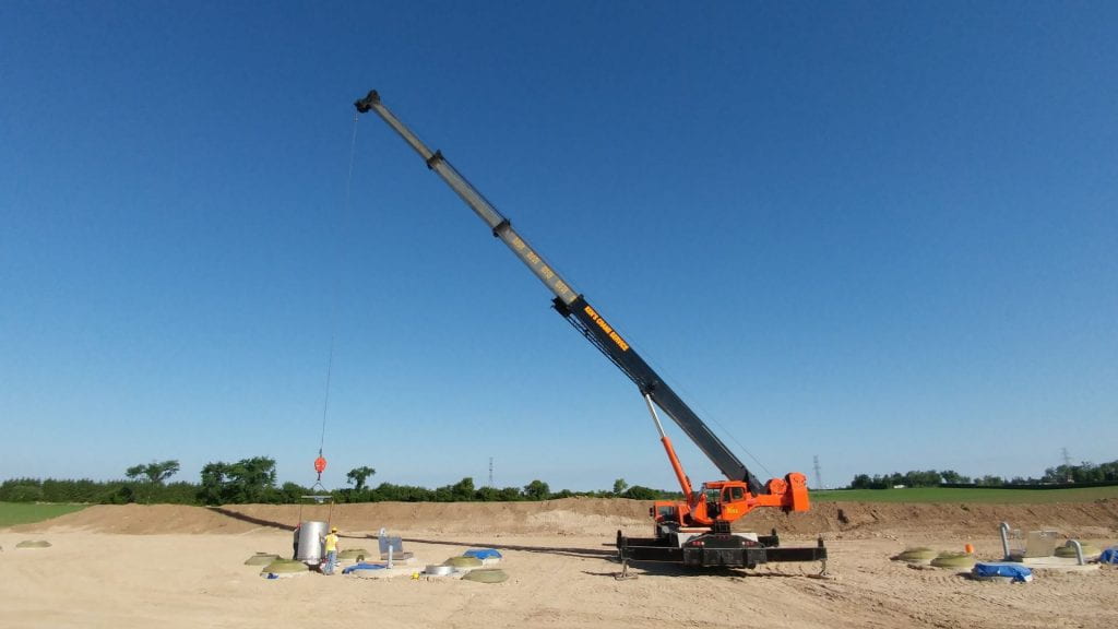 Large crane carrying soil core in an agricultural field